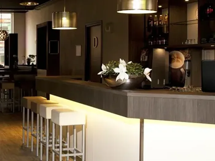Balcão de bar iluminado montado em salão, com banquetas e backbar