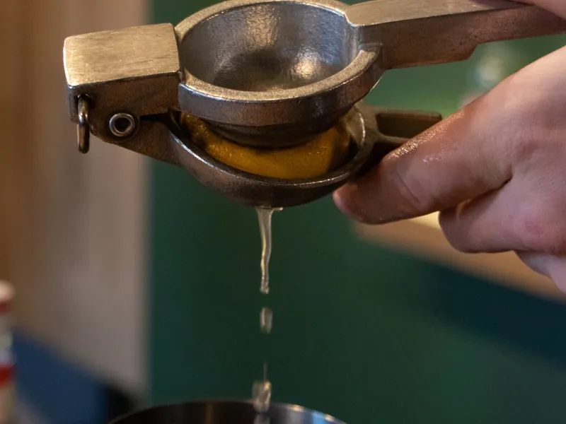 Bartender espremendo limão fresco na coqueteleira durante aula prática